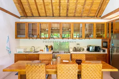 a kitchen with wooden cabinets and a wooden table at Villa Kainara Seminyak by RPM in Seminyak