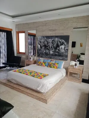 a bedroom with a large bed with a painting on the wall at Villa Filo's Paradise Pool n Spa. Seminyak in Seminyak