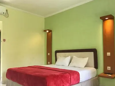 a bedroom with a large bed with a red blanket at Pondok Mesari Padma Legian RedPartner in Legian
