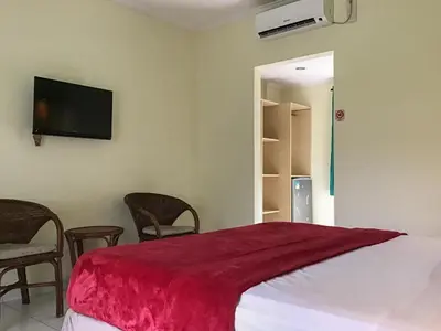 a bedroom with a bed with a red blanket on it at Pondok Mesari Padma Legian RedPartner in Legian