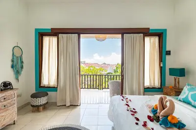 a bedroom with a bed and a view of a balcony at Spacious and Quiet 2 Bd Villa with Pool and Projector in Kerobokan