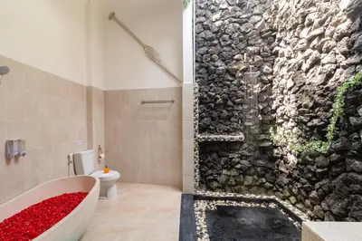 a bathroom with a bath tub and a stone wall at Spacious and Quiet 2 Bd Villa with Pool and Projector in Kerobokan