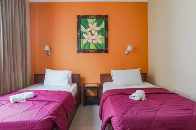 two beds sitting next to each other in a room at Taxa Uma Guest House in Kuta