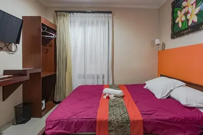 a bedroom with a large bed with a purple blanket at Taxa Uma Guest House in Kuta