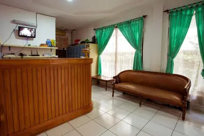 a living room with a couch and a television at Segara Sadhu Inn Kuta by ecommerceloka in Kuta