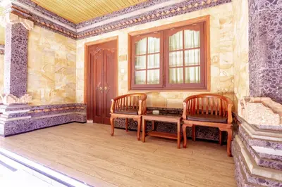 a room with two chairs and a table and a window at Segara Sadhu Inn Kuta by ecommerceloka in Kuta