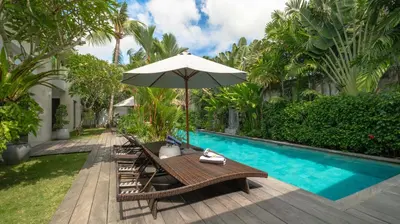 a table with an umbrella next to a swimming pool at Villa Nikaia by Villa Finder in Seminyak