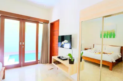 a bedroom with a bed and a sliding glass door at Jas Green Villas and Spa in Seminyak