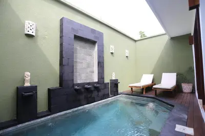 a swimming pool in the middle of a house with two chairs at Jas Green Villas and Spa in Seminyak