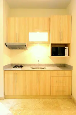 a kitchen with wooden cabinets and a sink and a microwave at Jas Green Villas and Spa in Seminyak
