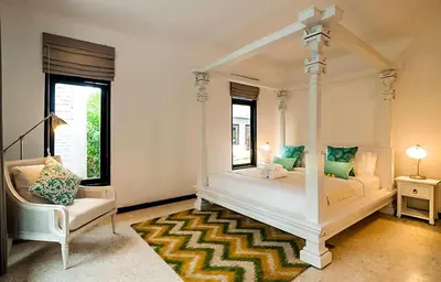 a bedroom with a white canopy bed and a chair at The Indies Estate in Sanur