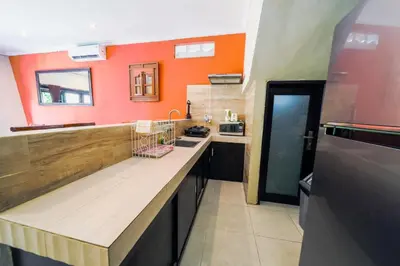 a large kitchen with orange walls and a counter at Pondok DEWI Villa - LEGIAN - 6 Bedroom Villa - Great Location in Legian