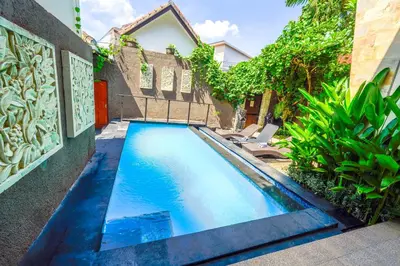 a swimming pool in front of a house with two chairs at Pondok DEWI Villa - LEGIAN - 6 Bedroom Villa - Great Location in Legian