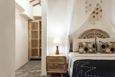 a bedroom with a bed and a lamp on a night stand at Madeira Javanese Joglo, Jimbaran in Jimbaran