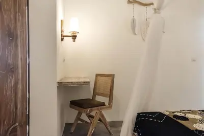 a chair sitting in a room with a bedroom at Madeira Javanese Joglo, Jimbaran in Jimbaran