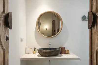 a bathroom with a stone sink and a mirror at Madeira Javanese Joglo, Jimbaran in Jimbaran