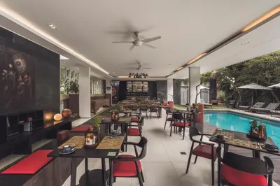 a restaurant with a pool and tables and chairs at Monolocale Resort & Spa Seminyak by Ini Vie Hospitality in Seminyak