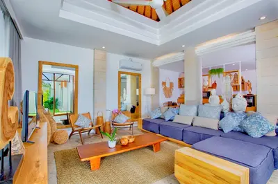 a living room with a blue couch and a table at THE MILAGRO VILLA in Canggu