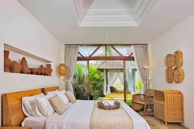 a bedroom with a bed and a large window at THE MILAGRO VILLA in Canggu