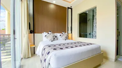 a bedroom with a large white bed and a balcony at Ultimate Residence Bali in Denpasar