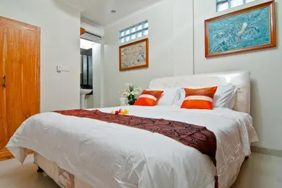 a bedroom with a large white bed with orange pillows at Kuta EcoStay in Kuta