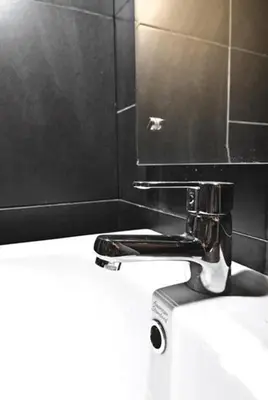 a bathroom with a toilet with a faucet on top of it at Kuta EcoStay in Kuta