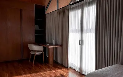 a bedroom with a desk next to a large window at ASAI Village in Jimbaran