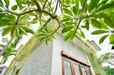 a white house with palm trees in front of it at Villa Cleopatra Bali in Sanur
