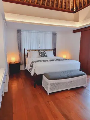 a bedroom with a large bed and two lamps on the floor at Calm Villa in Seminyak