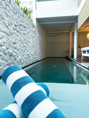 a swimming pool with blue and white towels next to a building at Calm Villa in Seminyak