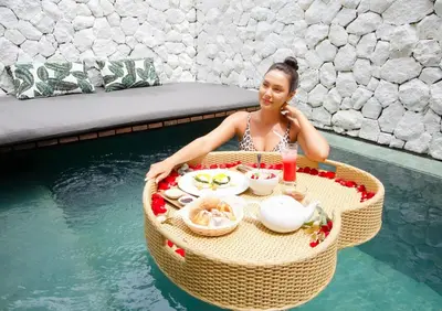 a woman sitting in a table in the water at Calm Villa in Seminyak