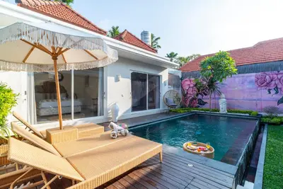 a swimming pool with two chairs and an umbrella at Villa Luna Rose in Seminyak