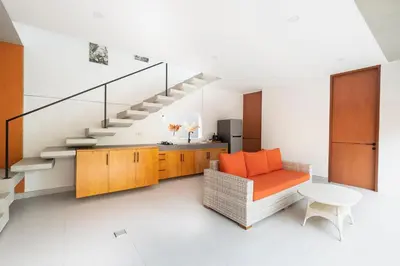 a living room with an orange couch and stairs at THE COINS VILLA SEMINYAK in Seminyak
