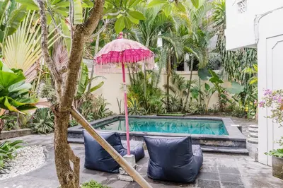 an umbrella and chairs next to a swimming pool at Dreams Villa -Private Pool, Fast Wifi, 2 min to Double Six Beach in Seminyak