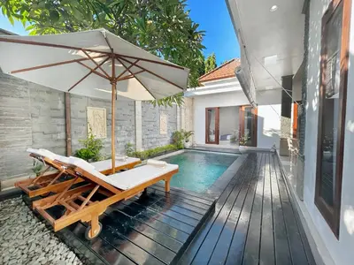 a pool with a chair and an umbrella next to a house at CASA BISMA - 3 Bedroom Villa with Pool in LEGIAN in Seminyak