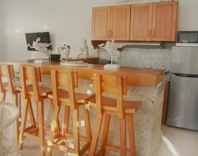a kitchen with a island with wooden chairs and a counter top at CASA BISMA - 3 Bedroom Villa with Pool in LEGIAN in Seminyak