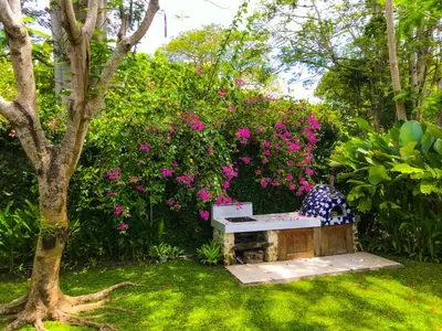 a bench in a garden with pink flowers at Chanteak Bali - Stone House 1 in Jimbaran