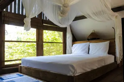 a bedroom with a bed with a large window at Chanteak Bali - Stone House 1 in Jimbaran