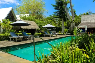 a pool at a resort with chairs and umbrellas at Chanteak Bali - Stone House 2 in Jimbaran