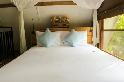 a bedroom with a white bed with blue pillows at Chanteak Bali - Stone House 2 in Jimbaran