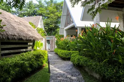 a path leading to a house with a thatch roof at Chanteak Bali - Stone House 2 in Jimbaran