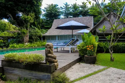 a patio with a bear statue next to a pool at Chanteak Bali - Stone House 3 in Jimbaran