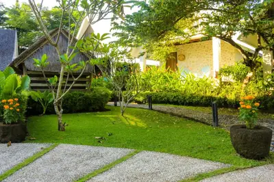 a garden with trees and plants in front of a house at Chanteak Bali - Stone House 3 in Jimbaran