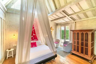 a bedroom with a canopy bed with a red hat on it at Chanteak Bali - Teak House 1 in Jimbaran