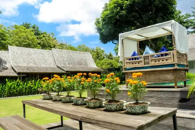 a group of flowers on a wooden table with a gazebo at Chanteak Bali - Teak House 1 in Jimbaran