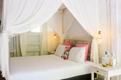 a bedroom with a white canopy bed with pink and white pillows at Chanteak Bali - Teak House 2 in Jimbaran