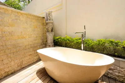 a bath tub sitting on a deck in a bathroom at Chanteak Bali - Teak House 3 in Jimbaran