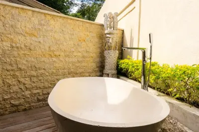 a bath tub sitting on a deck next to a wall at Chanteak Bali - Teak House 3 in Jimbaran