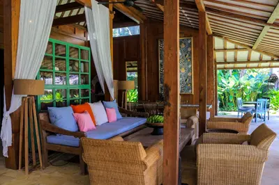 a living room with a blue couch with colorful pillows at Chanteak Bali - White House 1 in Jimbaran