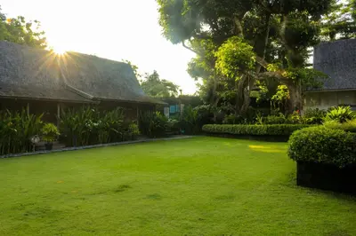a large yard with green grass and a house at Chanteak Bali - White House 1 in Jimbaran